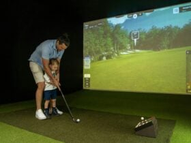 A father teaches his young son how to putt using the golf simulator