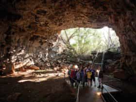 Tour group and guide in tube with opening in the background.
