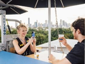 A woman smiles, taking a photo with her phone while sharing drinks with a man at Vertigo.