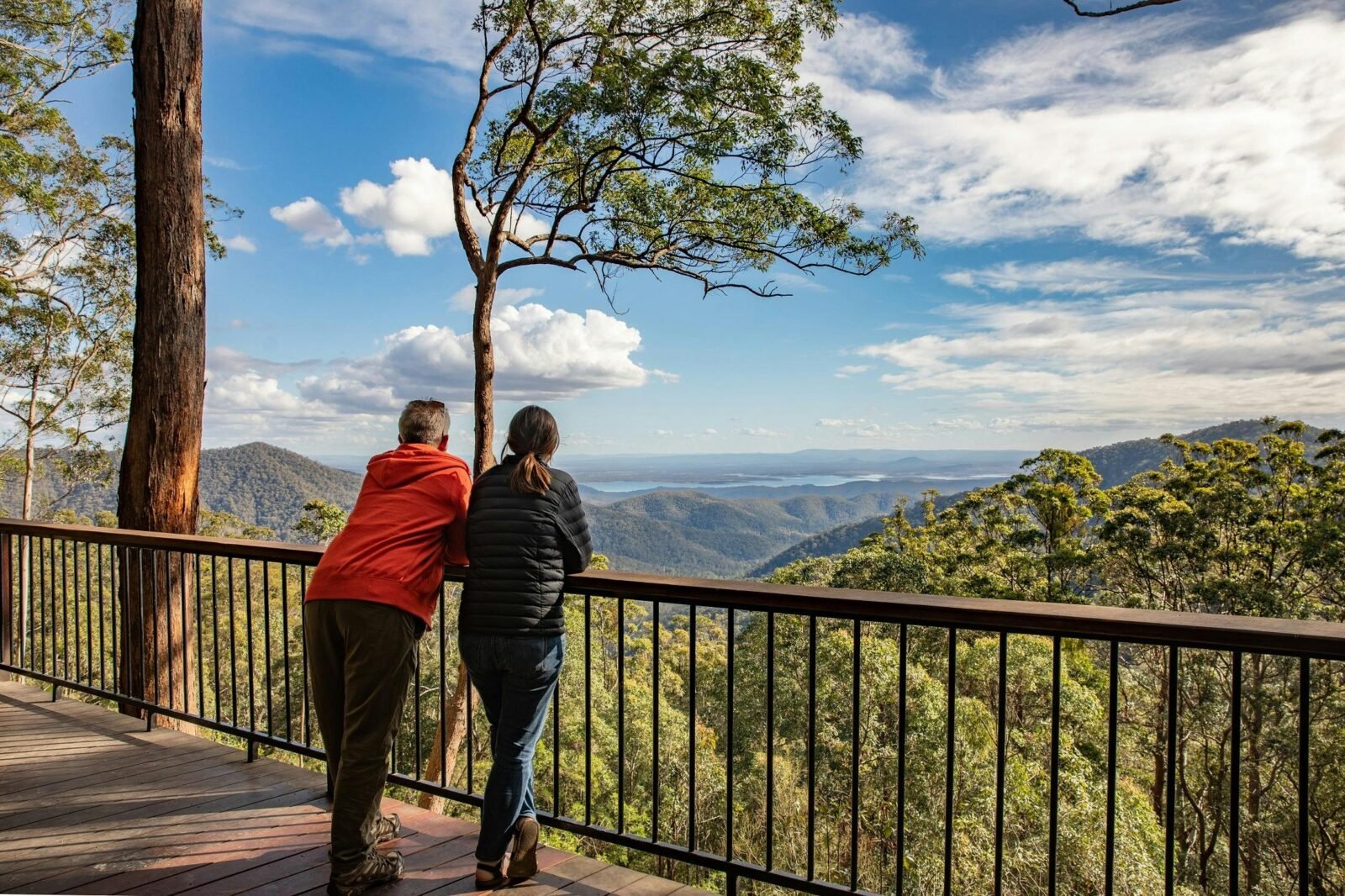 A middle aged couple leaning on a Lookout guardrail viewing the mountain ranges