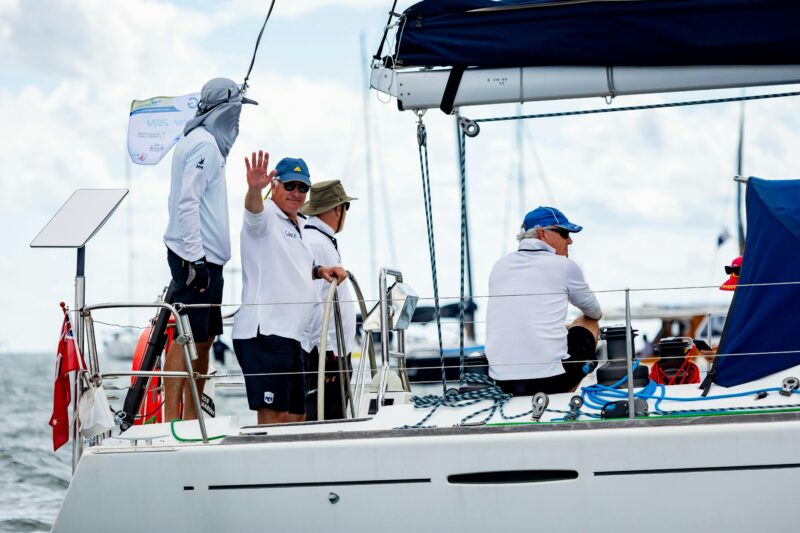 Four sailors with one waving at the camera from their yacht