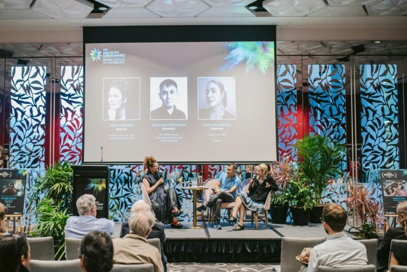 Three people on panel discussion with screen behind them