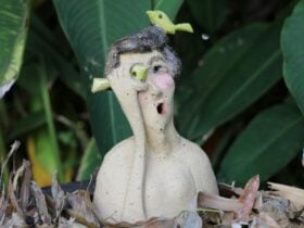 clay figure of a woman with her hand to her mouth and a bird on her hat