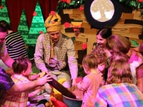 A man dressed up like a tree and playing with babies in a toy forest.