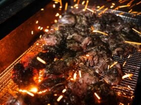 Jerk chicken cooking on coals with sparks flying