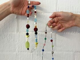 Two hands holding colourful beaded necklaces