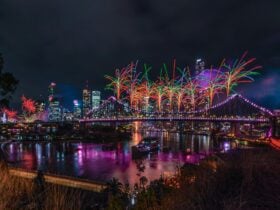Bright orange and green fireworks explode from the Story Bridge