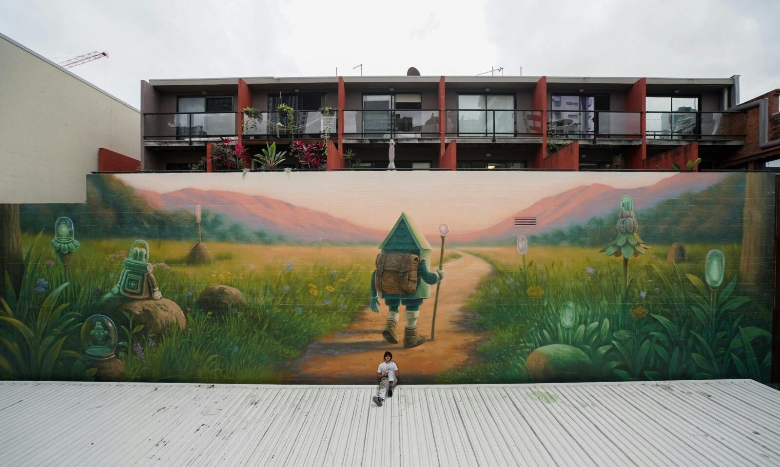 Mural of Leansy character carrying a bag pack and walking a dirt path towards the mountains