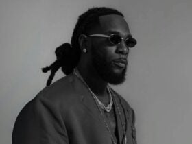 Black and white image of Burna Boy wearing sunglasses and hair tied back.