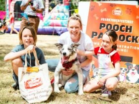 two kids and their mom smiling while holding a dog