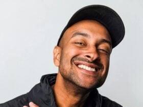 Person in a black jacket and cap against a plain light background.