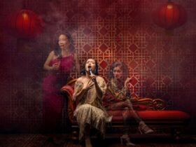 A women singing at karaoke and two women ghosts sits beside her looking annoyed.