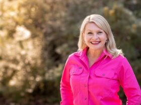 Ranger Stacey in a bright pink shirt with native bushland in the background