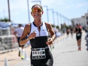 A person wearing a trisuit and sunnies whilst on the run leg of their triathlon race.