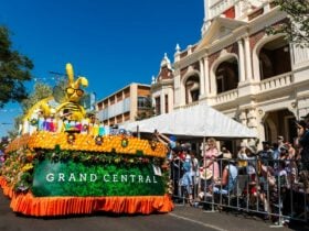 The grand central floral parade float with flowers and bee all decorated on it. People cheering