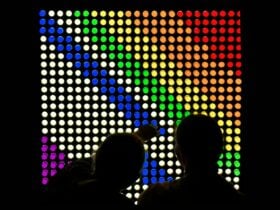 A photograph of children creating a colourful design on a large lightbox