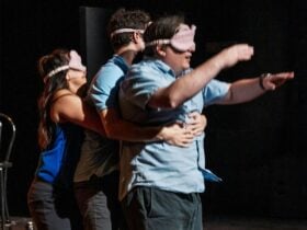 Three Blah Blah Blah Improv comedians with blindfolds on in a three-person Heimlich maneuver