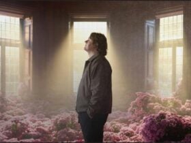 Lewis Capaldi in a dim lit room surrounded by pink flowers
