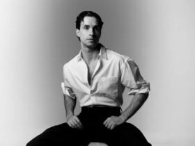 Black and white photo of comedian Louis Hanson in a white shirt and black pants