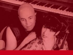 two people holding instruments and standing infront of a piano