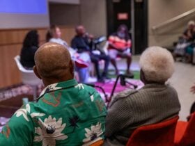 Framed from behind 2 people watching a talk in the Queensland Museum Theatre