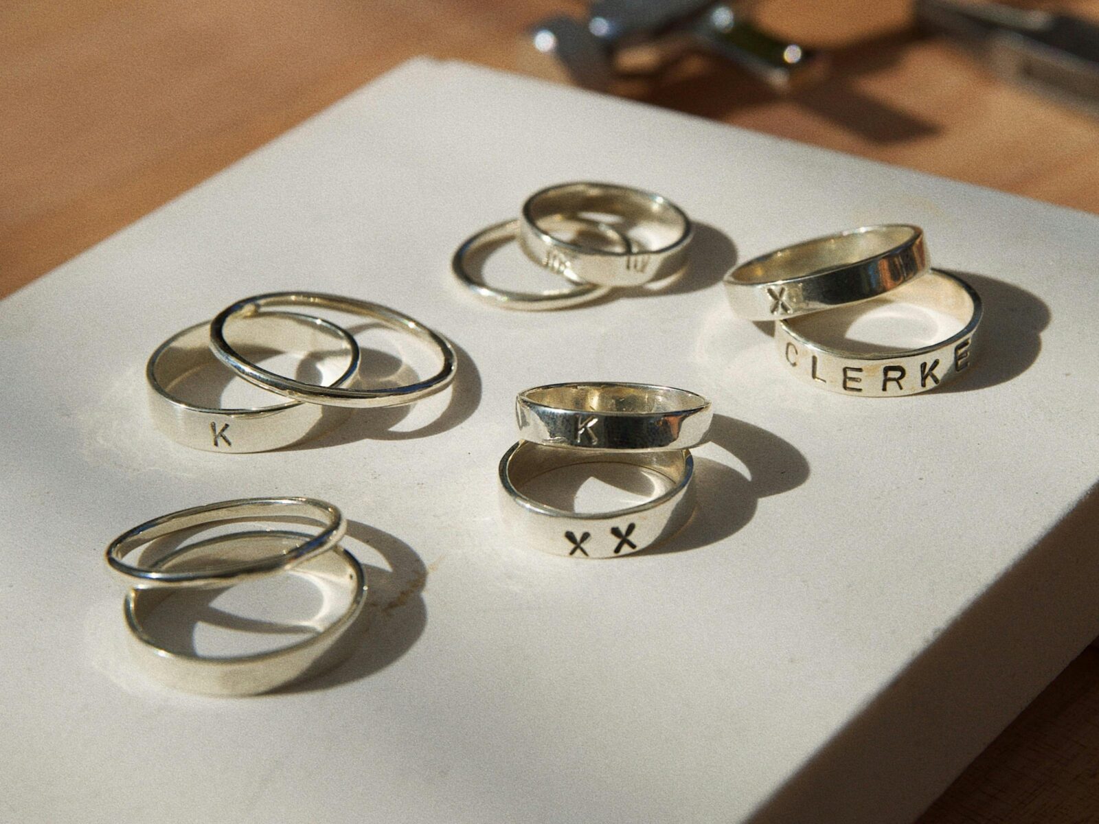 Handmade silver rings with unique engravings, displayed on a white board in natural light.