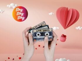 Hands displaying cassette tapes , "not so silly" and "love songs", against a pink backdrop