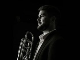 A striking black and white portrait of a bearded trombone player, facing the light.