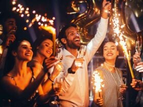 Man in white shirt with three women cel.ebrating with sparklers.