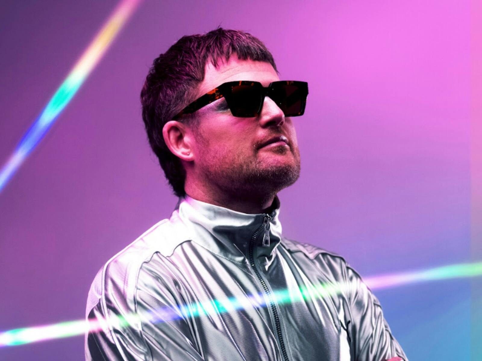 The artist peforming in a silver suit and glasses on