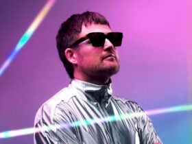 The artist peforming in a silver suit and glasses on