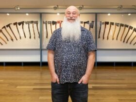 Mikey Hilburger smiling in front of his axe collection