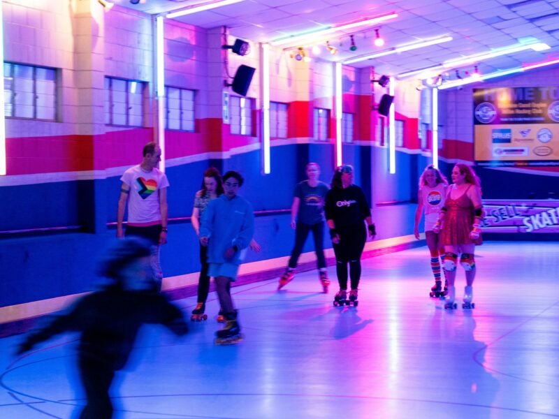 Several people skating on a colourfully lit rink