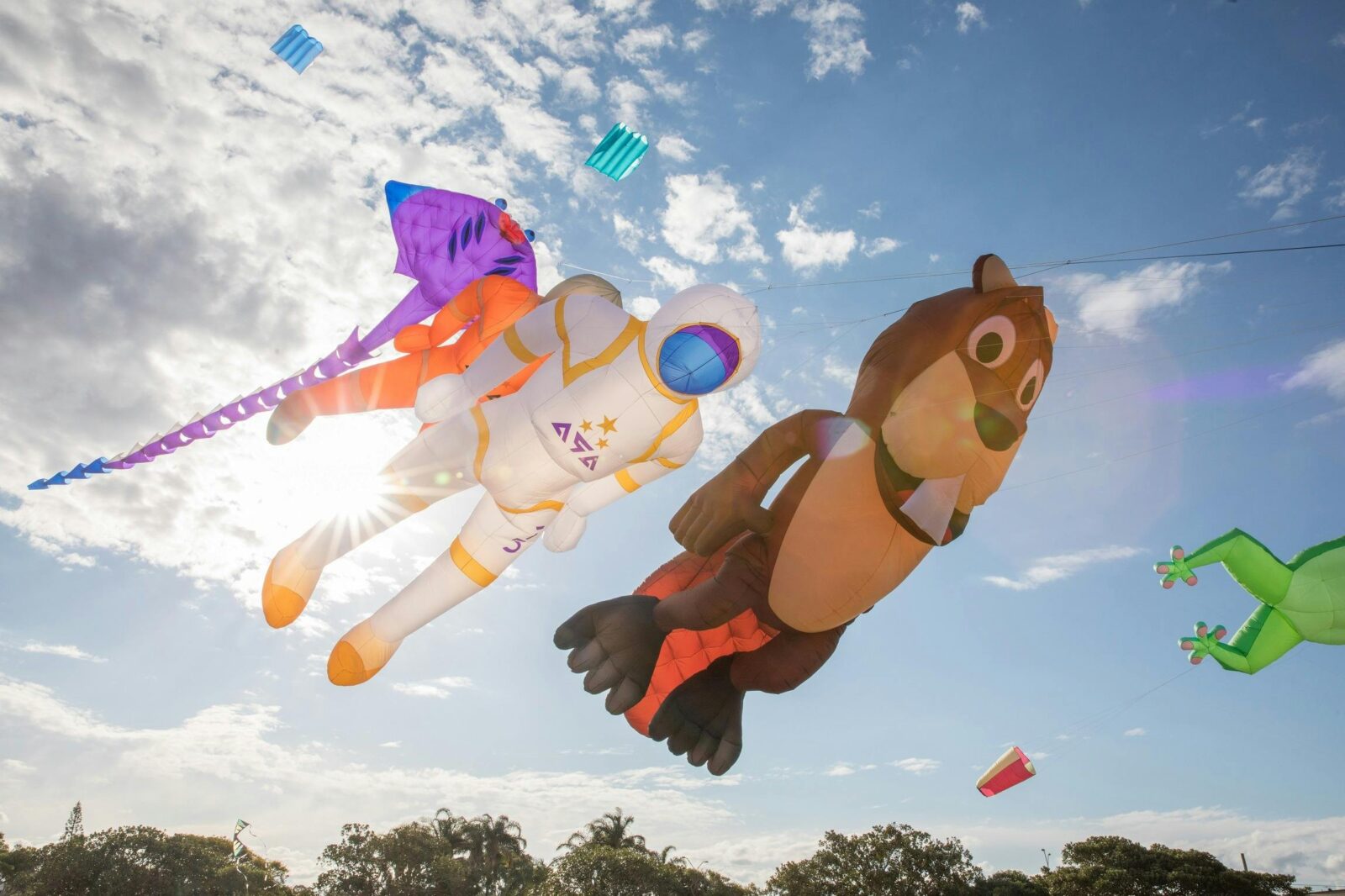 Large bear, astronaut and sting ray kites flying in the sky
