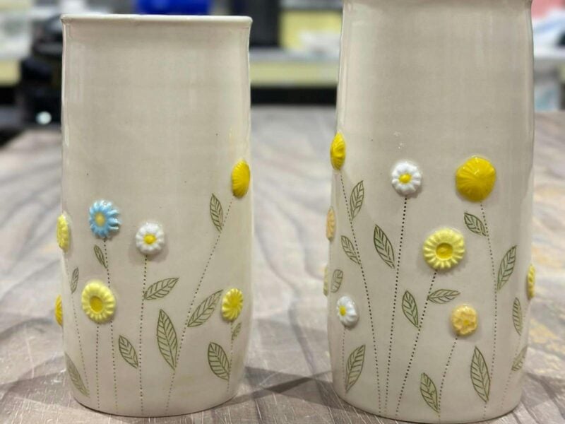 2 ceramic vases decorated with colourful flowers.