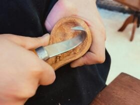 The head of a wooden spoon is carved with a tool.