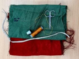 Image of green and red fabrics with scissors and thread layered ontop