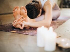 Woman stretching forward in a yoga pose, candles on the ground