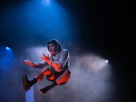 A young man in a grey hoodie jumping in the air