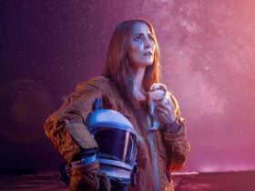 Women in a spacesuit looking in to the distance while holding a guinea pig