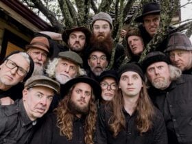 A close up of a group of men of mixed age, wearing black hats and pulling funny faces.