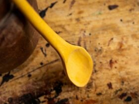 Close-up of carved wooden spoon leaned up against a tin with the spoon end resting down.