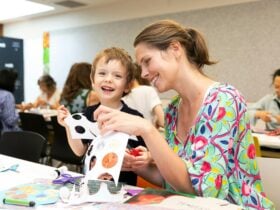 Mum and son enjoying a craft workshop laughing and cutting paper