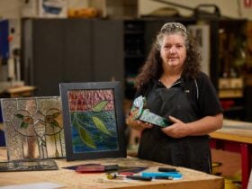 Woman displaying created stained-glass panels.