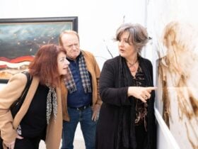 Artist Christa Coetzee explaining her artwork hanging in her private studio