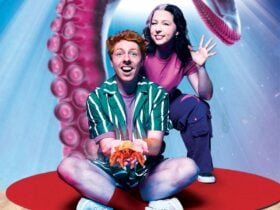 A boy holding a crab and a girl sitting in front of octopus tentacle