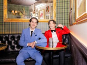 Two men dressed in coloured suits, sitting in booth