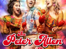 Three performers in tropical outfits stand with maracas, smiling at each other