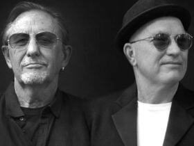 2 older men both with hats and sunglasses man on left with goatie beard man on right looking right