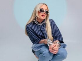 The singer posing for a photo behind a blue and grey backround